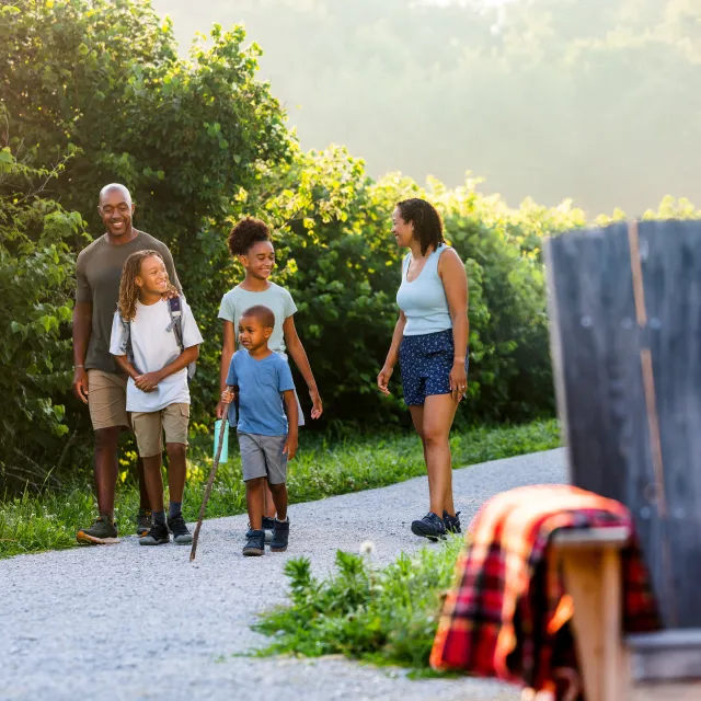 Family of five walks along a gravel path surrounded by greenery.