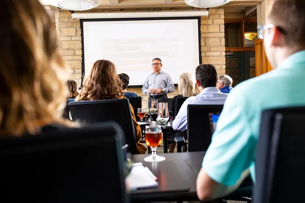 Man hosting meeting from front of the room in front of a projector