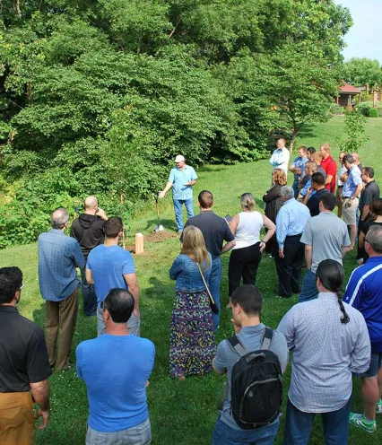 A group of people standing together in a grassy field, smiling and enjoying the outdoors.