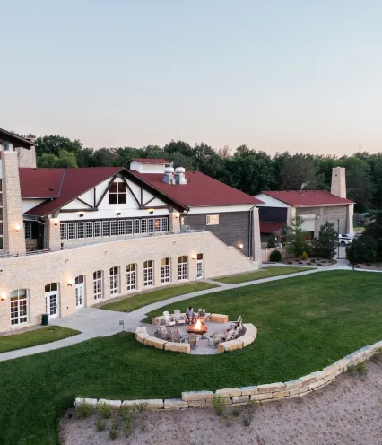 Aerial view of Lied Lodge with a stone facade, surrounded by greenery and a circular fire pit for gatherings.