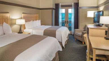 A guest room featuring two beds, a television, and a desk, providing a comfortable and functional space for guests.