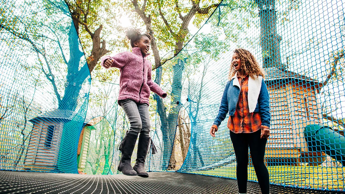 Child and mother jumping in the tree top adventure