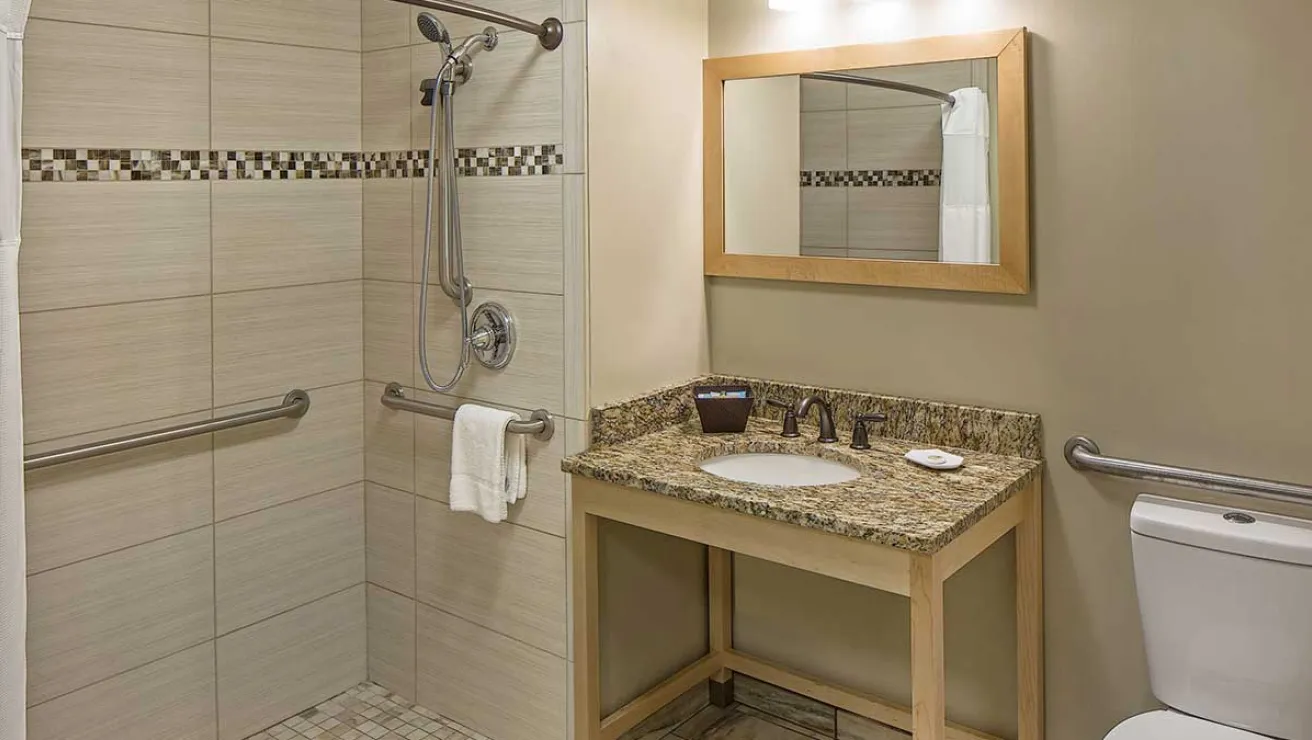 A bathroom featuring a shower stall, toilet, and sink, with neutral-colored walls and modern fixtures.