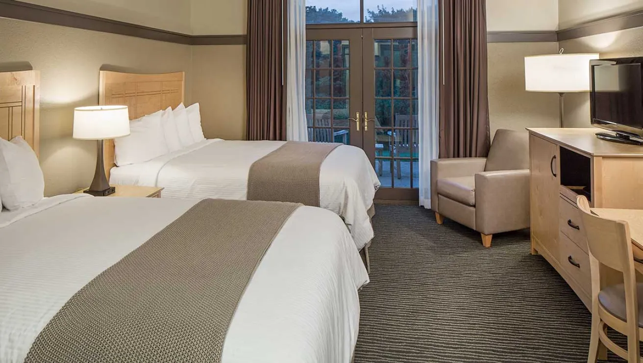 A hotel room featuring two beds, a television, and a desk, creating a comfortable and functional space for guests.