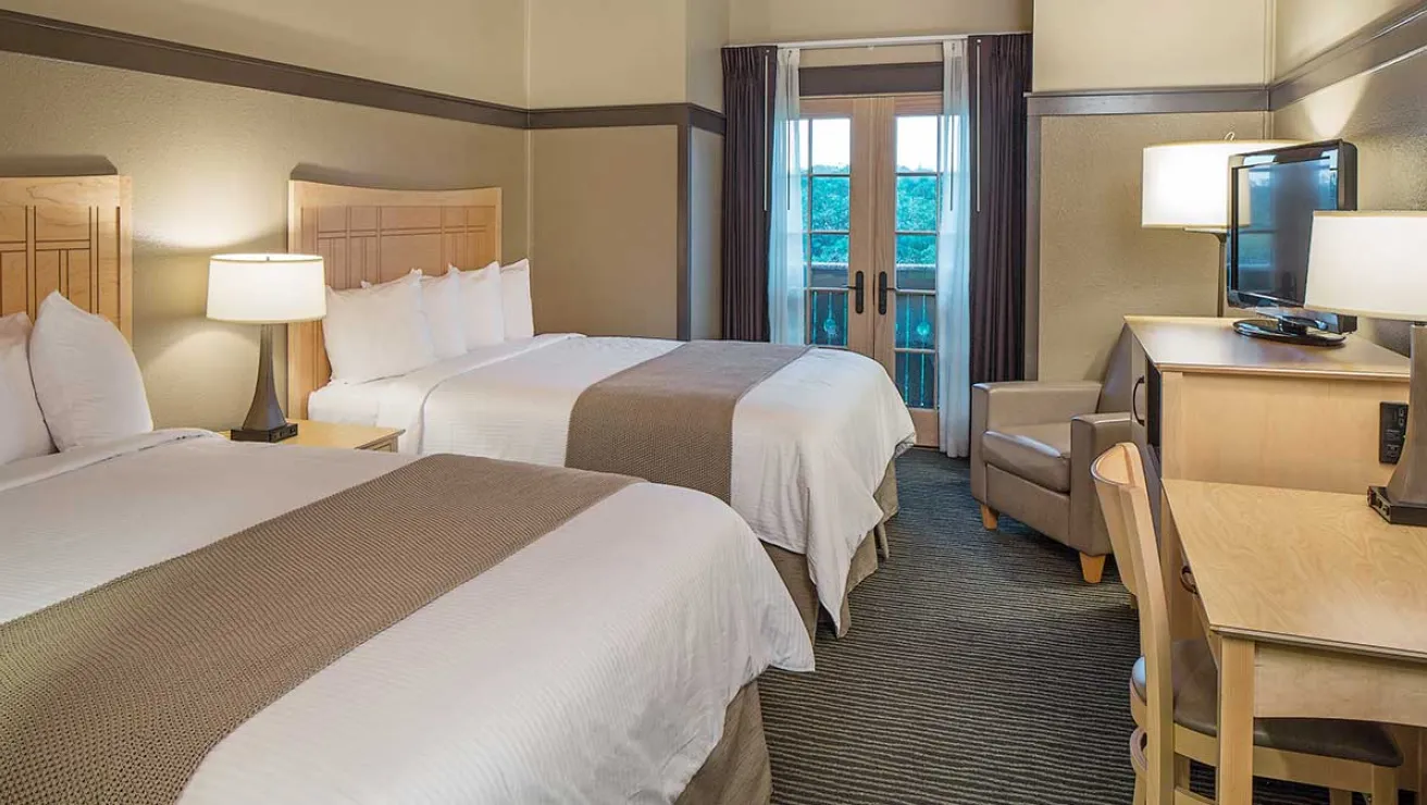 A hotel room featuring two beds, a television, and a desk, creating a comfortable and functional space for guests.