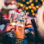 Group of people toasting with champaign glasses with a lit tree in the background